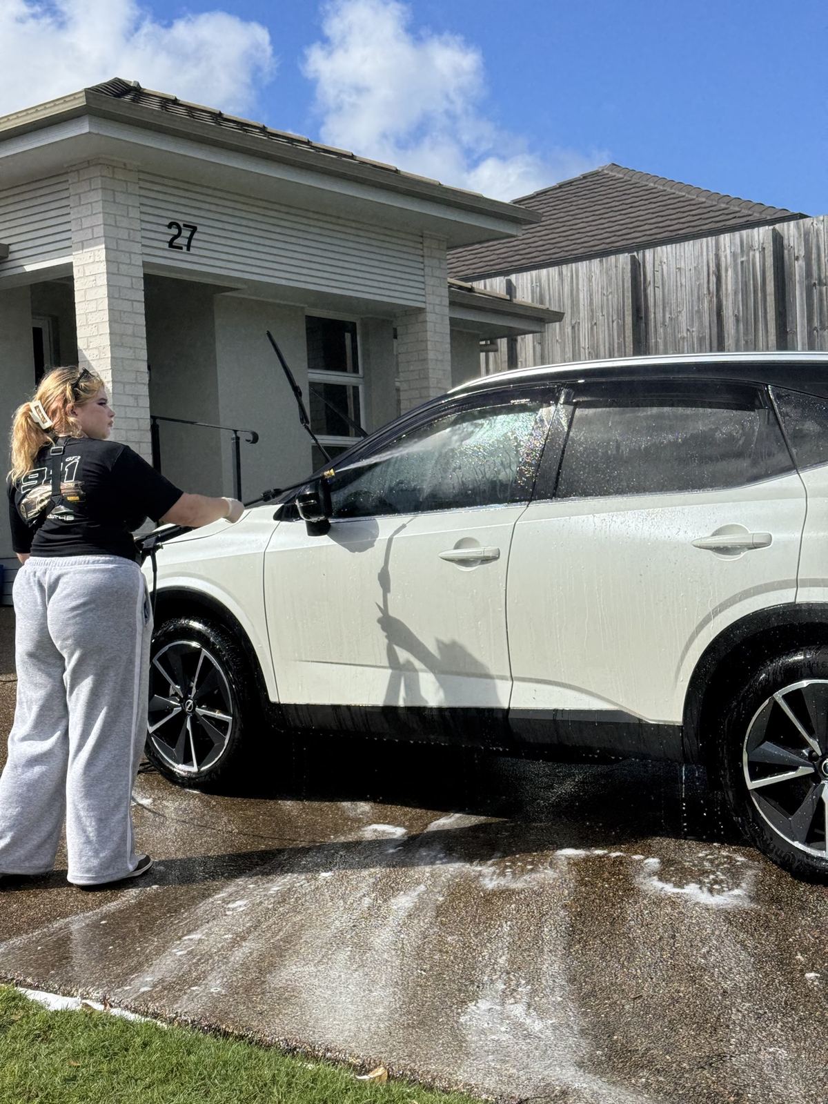 Rinsing snow foam off a white SUV during a mobile detail