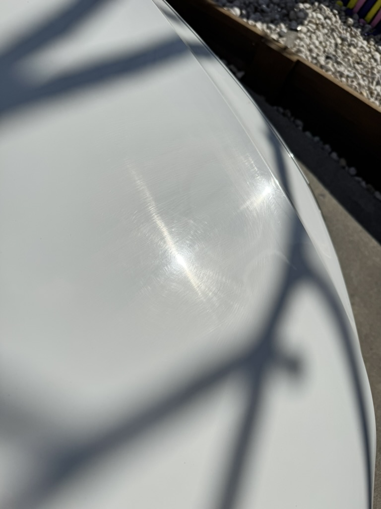 Swirl marks and fine scratches in white paint, visible in direct sunlight on a car in the Redlands